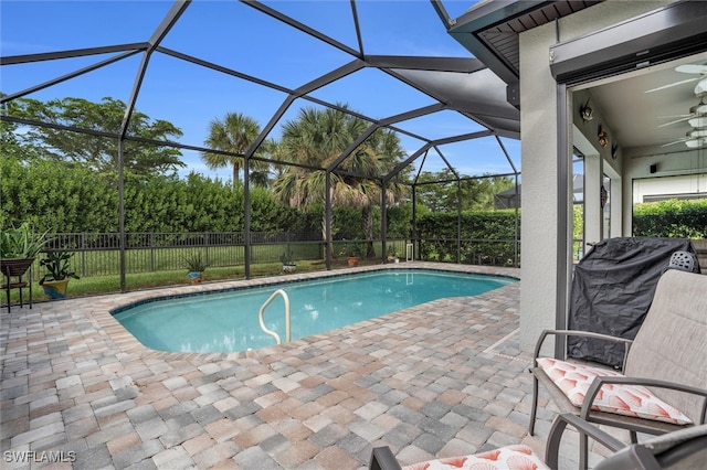 view of swimming pool featuring a patio, glass enclosure, and ceiling fan