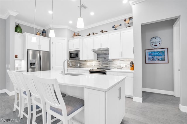 kitchen with pendant lighting, a center island with sink, white cabinets, sink, and appliances with stainless steel finishes