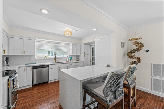 kitchen with a kitchen breakfast bar, stainless steel appliances, dark wood-type flooring, sink, and white cabinetry