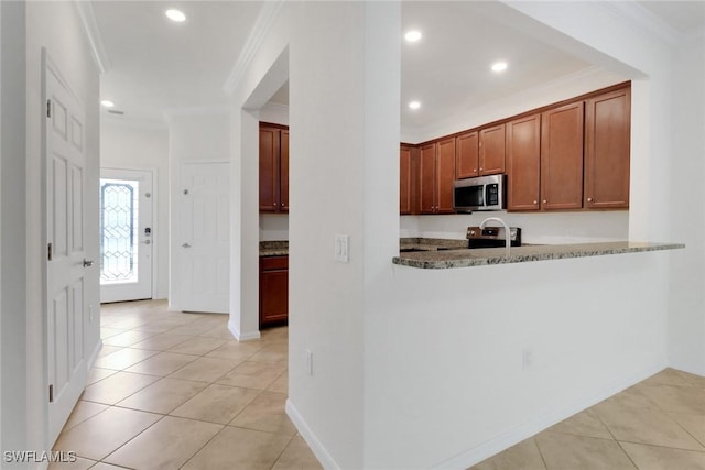 kitchen with light tile patterned flooring, crown molding, stainless steel appliances, and dark stone counters