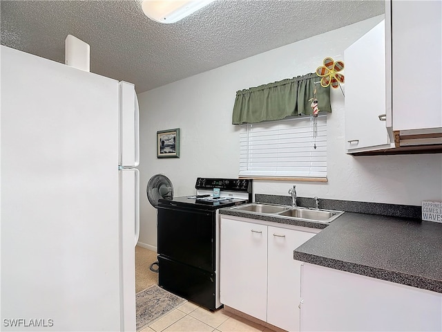 kitchen featuring freestanding refrigerator, white cabinets, electric range, and dark countertops