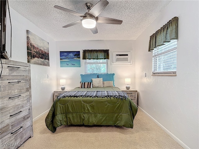 bedroom featuring a wall unit AC, carpet, baseboards, and a textured ceiling