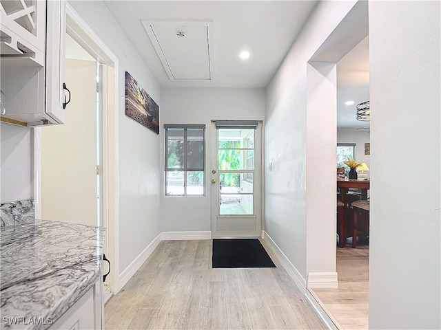 doorway featuring light wood finished floors and baseboards