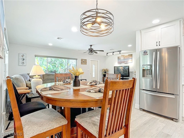 dining area featuring light wood-style flooring, recessed lighting, ceiling fan with notable chandelier, visible vents, and track lighting