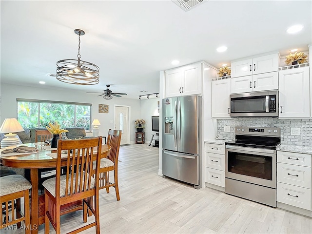 kitchen with tasteful backsplash, white cabinetry, stainless steel appliances, and light stone counters