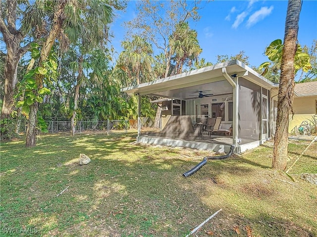 rear view of property with a sunroom, ceiling fan, a lawn, and fence