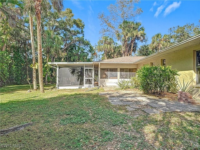 view of front of property featuring a front yard, a sunroom, and stucco siding