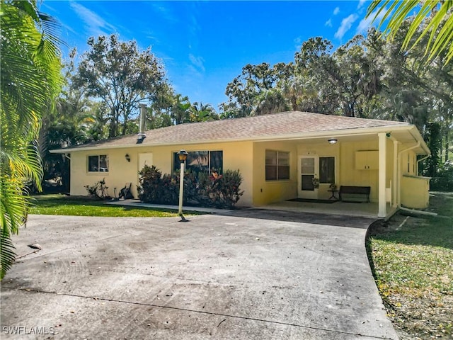 ranch-style home with a front yard, driveway, and stucco siding