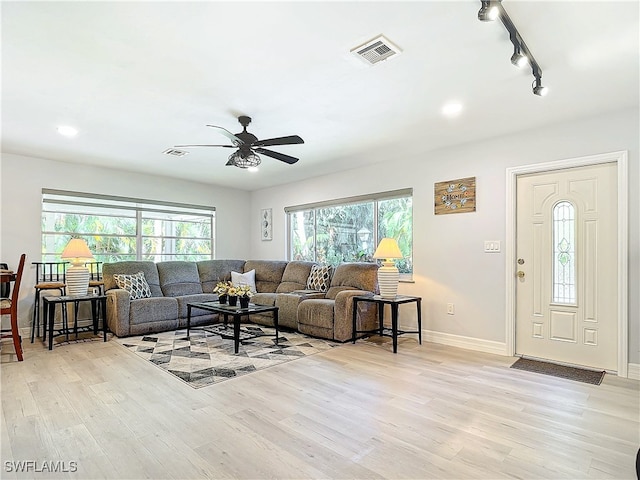 living area with light wood-type flooring, rail lighting, baseboards, and visible vents