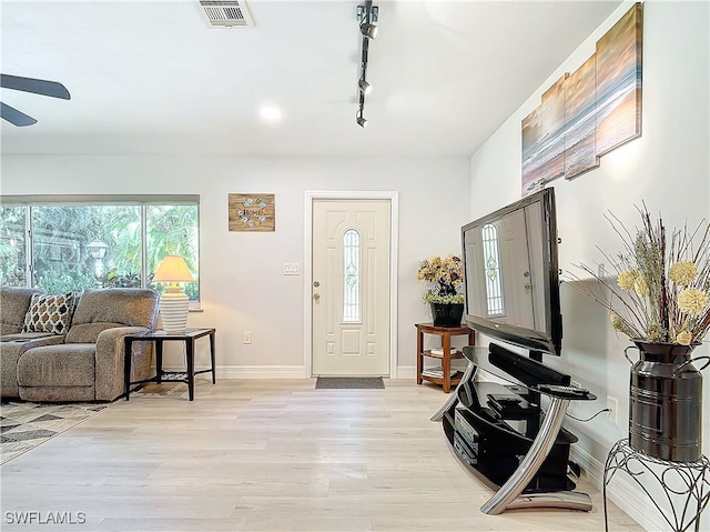 entryway featuring light wood finished floors, track lighting, visible vents, and baseboards