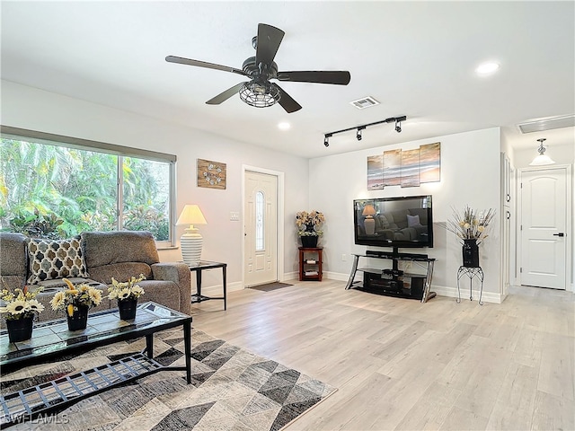 living area featuring baseboards, ceiling fan, and light wood-style floors