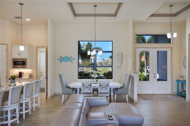 dining area with a high ceiling, a tray ceiling, plenty of natural light, and a notable chandelier