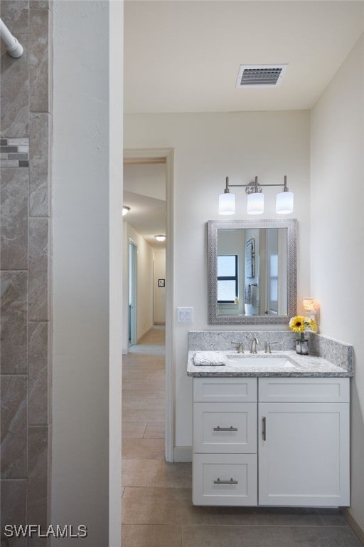 bathroom featuring tile patterned flooring, vanity, and a tile shower