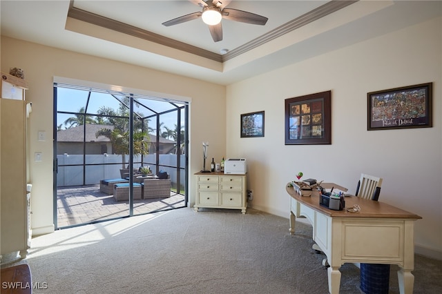 office space featuring ceiling fan, light colored carpet, crown molding, and a tray ceiling