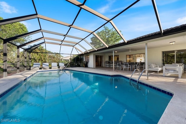 view of pool featuring outdoor lounge area, a patio area, ceiling fan, and a lanai