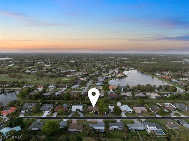 aerial view at dusk featuring a water view