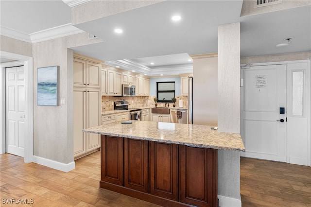 kitchen with kitchen peninsula, appliances with stainless steel finishes, light wood-type flooring, light stone counters, and cream cabinets