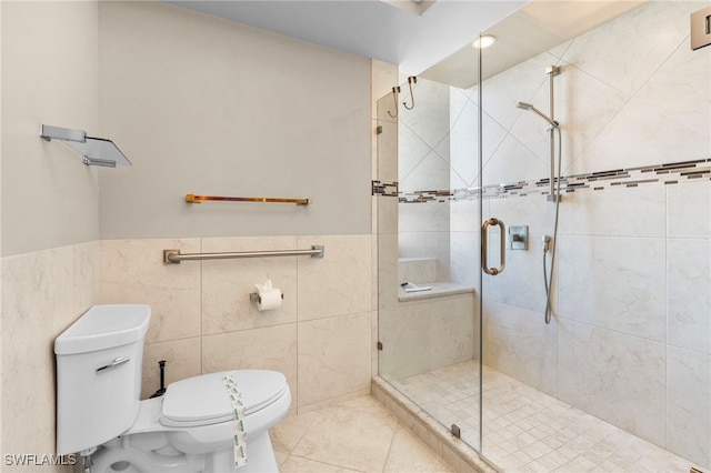 bathroom with tile patterned flooring, toilet, a shower with shower door, and tile walls