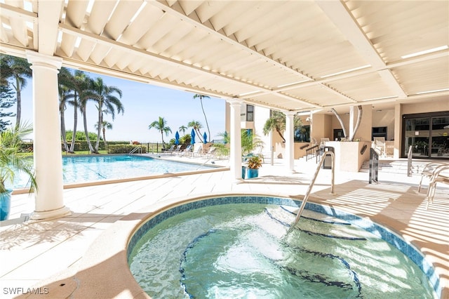 view of pool with a patio area, a bar, and a hot tub