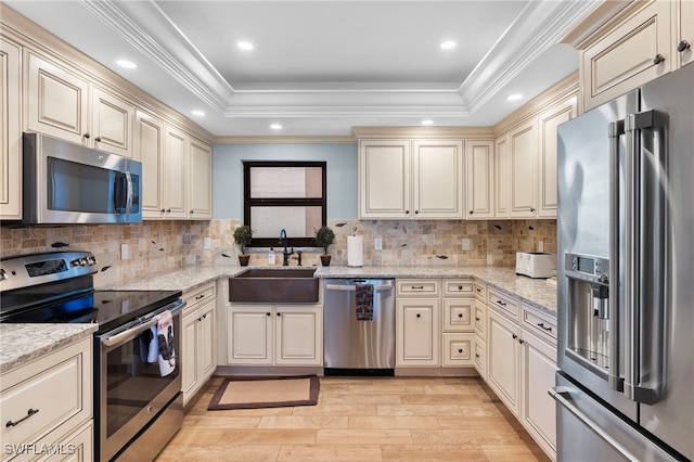 kitchen with ornamental molding, sink, stainless steel appliances, and cream cabinetry