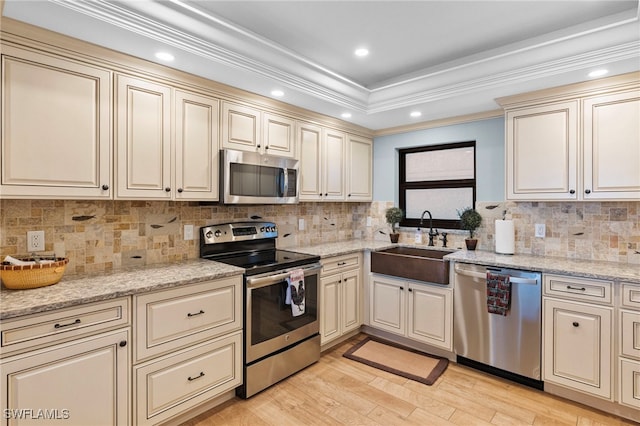 kitchen featuring ornamental molding, cream cabinets, stainless steel appliances, and sink