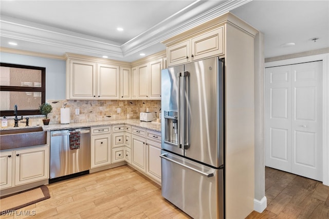 kitchen with light stone countertops, cream cabinets, light hardwood / wood-style flooring, and appliances with stainless steel finishes