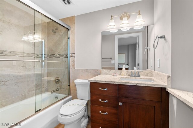 full bathroom featuring vanity, enclosed tub / shower combo, and toilet