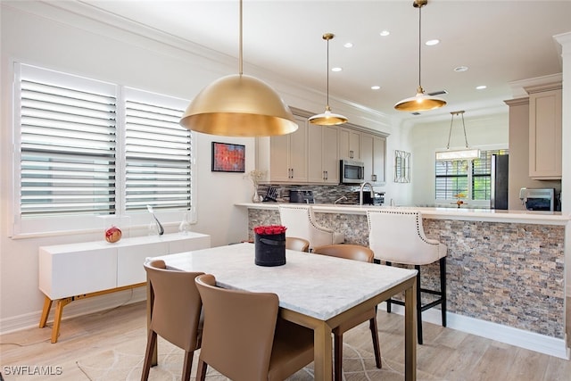 dining area featuring crown molding, sink, and light hardwood / wood-style floors