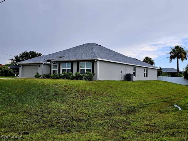 view of side of home with a yard, a garage, and central AC unit