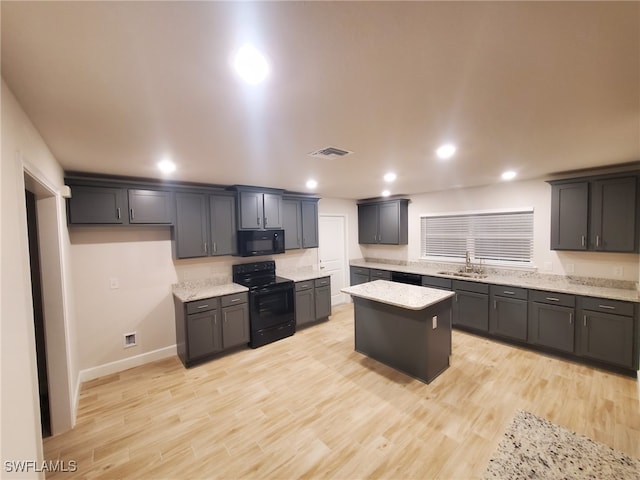 kitchen featuring light stone countertops, a center island, black appliances, and light hardwood / wood-style floors