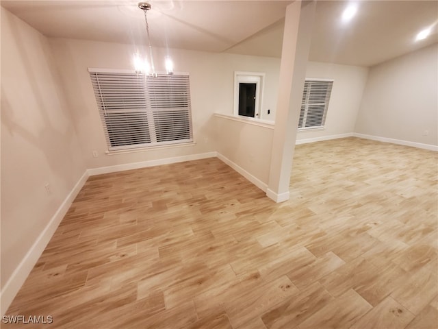 unfurnished room with light hardwood / wood-style floors and an inviting chandelier