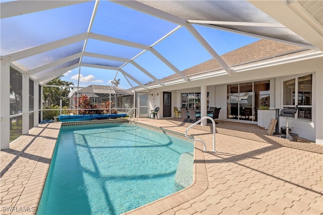 view of pool with glass enclosure and a patio area