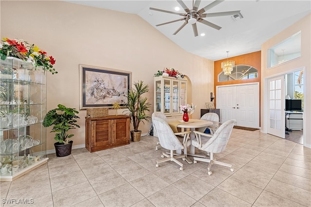 dining space with light tile patterned floors, ceiling fan with notable chandelier, and high vaulted ceiling