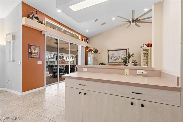 kitchen with kitchen peninsula, ceiling fan, light tile patterned floors, and lofted ceiling