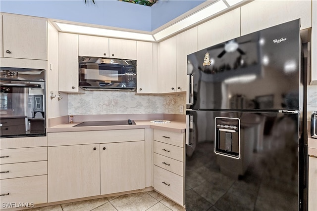 kitchen with cream cabinetry, light tile patterned floors, tasteful backsplash, and black appliances