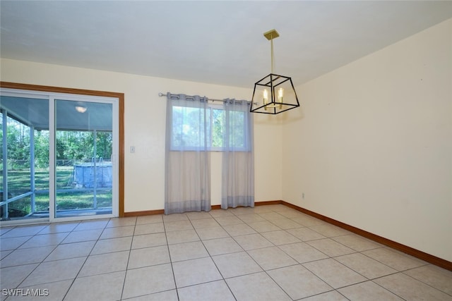 empty room featuring a notable chandelier and light tile patterned floors