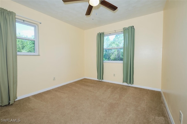 unfurnished room featuring light colored carpet, a wealth of natural light, and ceiling fan