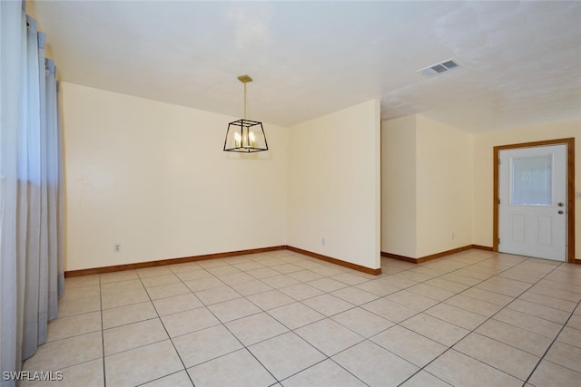 spare room featuring a notable chandelier and light tile patterned flooring