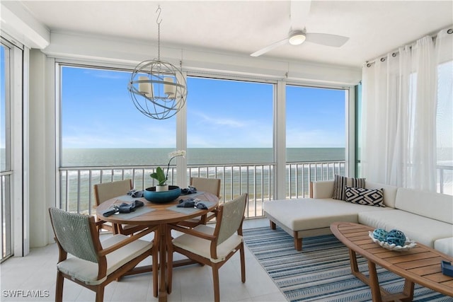 sunroom with a wealth of natural light, a water view, and ceiling fan with notable chandelier