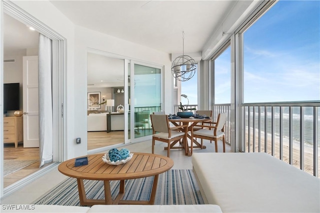 sunroom / solarium with a water view and a notable chandelier