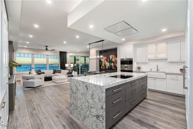 kitchen featuring a kitchen island, a water view, white cabinetry, and sink