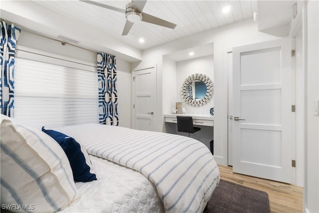 bedroom featuring ceiling fan, light hardwood / wood-style floors, built in desk, and wooden ceiling