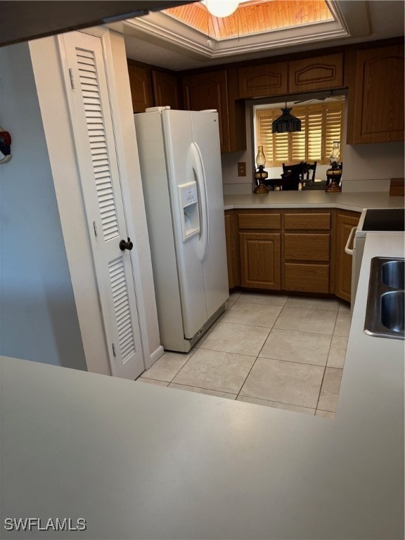 kitchen with sink, light tile patterned floors, white refrigerator with ice dispenser, and range