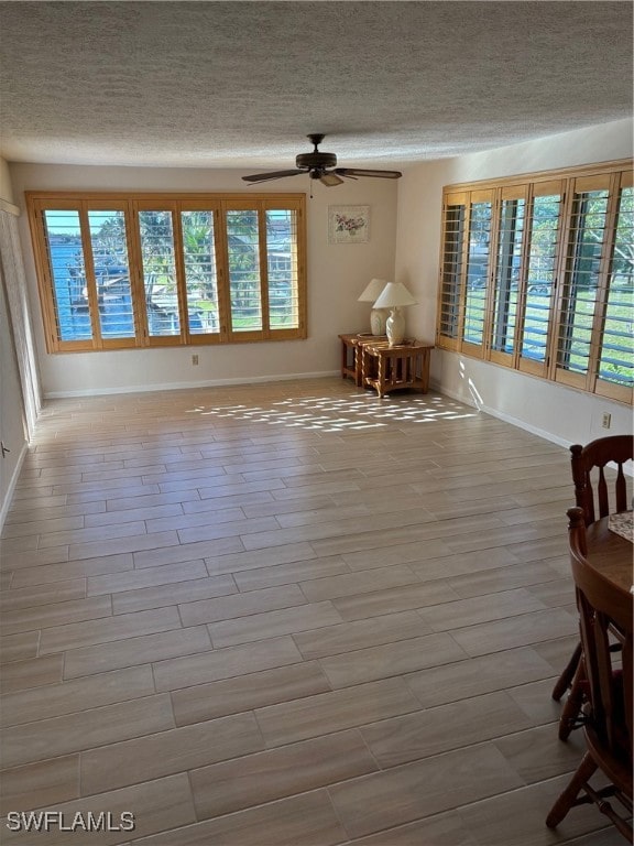 interior space featuring a textured ceiling, light wood-type flooring, plenty of natural light, and ceiling fan