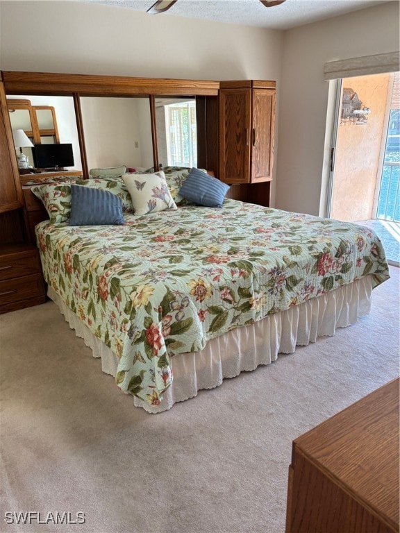 carpeted bedroom with multiple windows, ceiling fan, a textured ceiling, and access to exterior