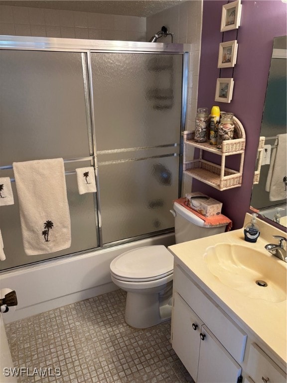 full bathroom with combined bath / shower with glass door, vanity, and toilet