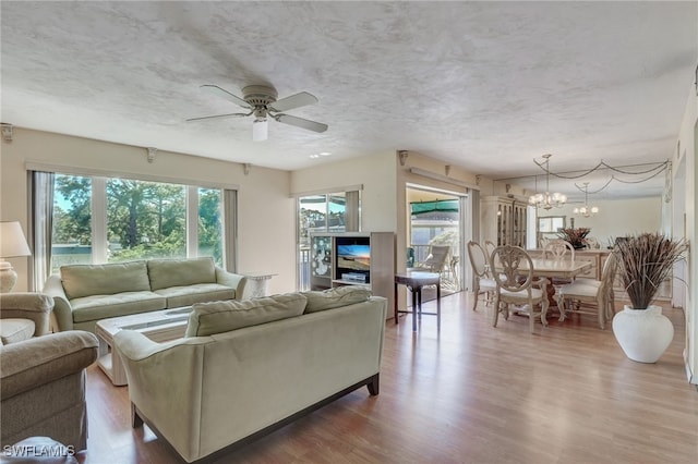 living room with wood-type flooring and ceiling fan with notable chandelier