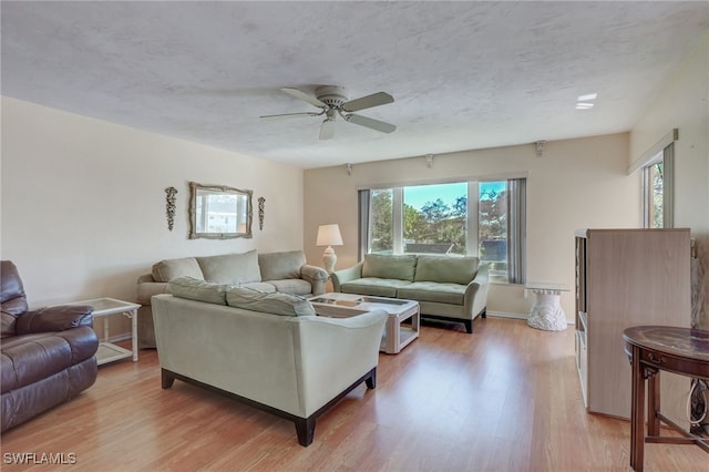 living room with ceiling fan, a textured ceiling, a wealth of natural light, and light hardwood / wood-style flooring