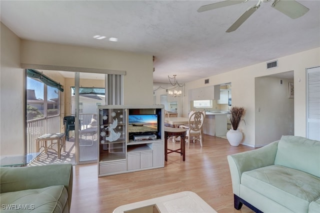 living room featuring light hardwood / wood-style floors and ceiling fan with notable chandelier