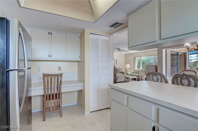 kitchen with ceiling fan with notable chandelier, white cabinetry, and stainless steel refrigerator